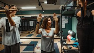Pilates instructor guiding two women during a workout in a modern gym environment.